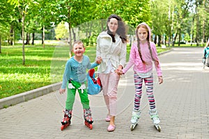 Family of mother and children on roller skates walks in a Sunny