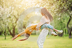 Family of mother and daughter in blooming cherry garden