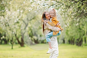 Family of mother and daughter in blooming cherry garden