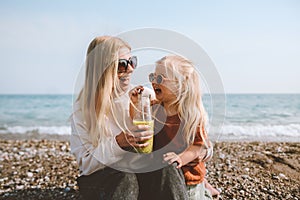 Family mother and daughter child drinking smoothie on beach healthy lifestyle