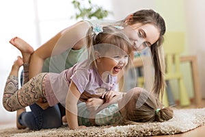 Family - mother and daughters having a fun on floor at home. Woman and children relaxing together.