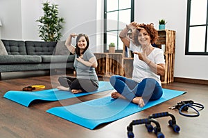 Family of mother and down syndrome daughter doing exercise at home smiling making frame with hands and fingers with happy face