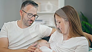 Family of mother, father and baby breastfeeding sitting on the sofa at home