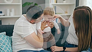 Family of mother, father and baby smiling sitting on the sofa at home