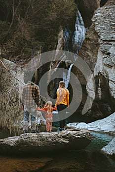 Family mother and father with child enjoying waterfall view hiking together outdoor travel lifestyle vacations