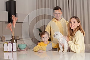 Family, mother and father with child son and white dog, three abstract plastic bottles on the white table