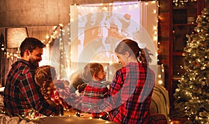 Family mother father and children watching projector, film, movies with popcorn in   christmas evening   at home
