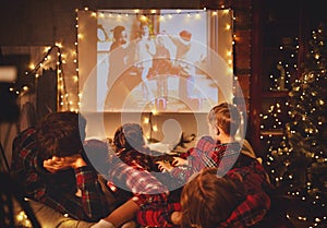 Family mother father and children watching projector, TV, movies with popcorn in   christmas evening   at home