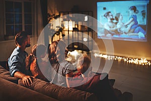 Family mother father and children watching projector, TV, movies with popcorn in   evening   at home