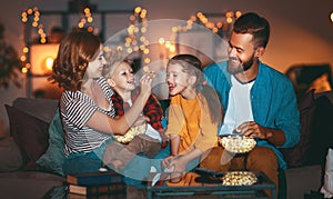 Family mother father and children watching projector, TV, movies with popcorn in   evening   at home photo