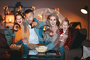 Family mother father and children watching projector, TV, movies with popcorn in   evening   at home