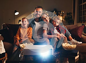 Family mother father and children watching projector, TV, movies with popcorn in   evening   at home