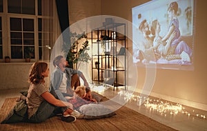 Family mother father and children watching projector, TV, movies with popcorn in   evening   at home