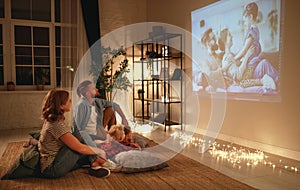 Family mother father and children watching projector, TV, movies with popcorn in   evening   at home photo