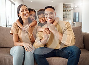 Family, mother and father with hugging kids relaxing on living room sofa with smile for quality bonding time at home