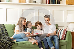 Family mother, father and kids reading interesting book