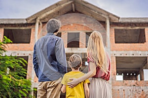 Family mother, father and son looking at their new house under construction, planning future and dreaming. Young family