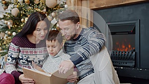 Family mother, father and son reading book and talking on Christmas Eve at home