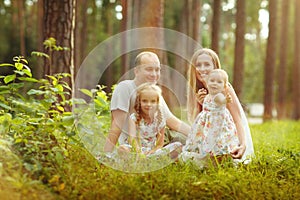 Family - mother, father and two daughters blonde sitting in a su