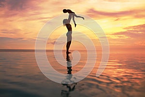 Family. Mother And Kid Silhouettes. Mom And Daughter Playing On Sea Beach. Beautiful Sunset Sky And People Reflection.