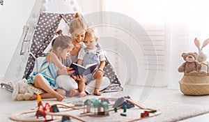 Family mother reading to children book in tent at home