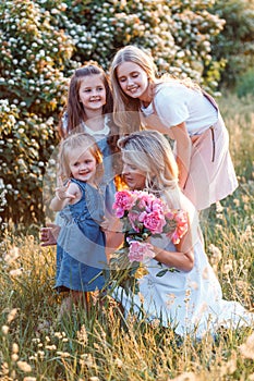 Ð family of mother and three cute daughters with peonees. Concept of happy motherhood