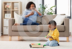 Baby playing toy blocks and mother with smartphone