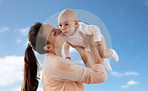 Happy mother kissing little baby boy over sky