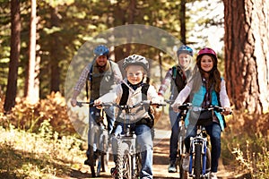 Family mountain biking on forest trail, front view photo