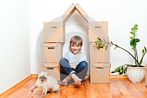 Family moves into a new apartment. Moving day. Happy child and cat having fun together at moving day in new home