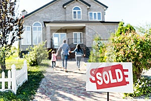 family moving into new house with sold signboard