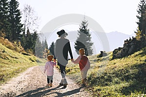 Family in nature outdoor. Woman with kids on hiking trail in mountains