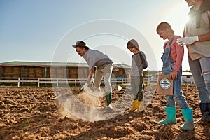 Family near dad dig ground on field to plant seeds