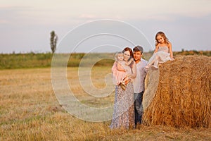 Family near haystacks on sloping field.