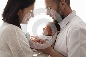 Family with Newborn Baby. Happy Parents holding one month Child. Smiling Mother and Father Silhouette with Infant over White