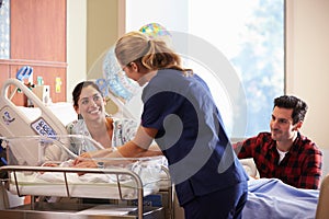 Family And Nurse With New Born Baby In Post Natal Department