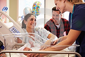 Family And Nurse With New Born Baby In Post Natal Department