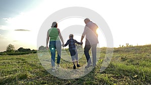 Family with one child walking into sunset at meadow