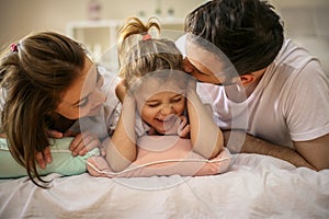 Family with one daughter lying on bed.