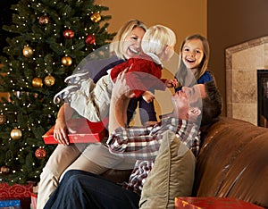 Family Opening Presents In Front Of Christmas Tree