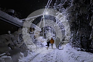 Family outdoor together at winter night, beautiful snowy landscape in countryside, group of people in street light