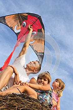The family outdoors flying kite in the sky