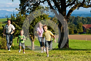 Family outdoors is running on a meadow