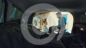 Family packing bags in car trunk