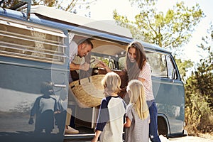 Family packing up their camper van for a road trip vacation