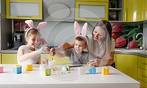 A family paints eggs in the kitchen in anticipation of the Easter holiday.