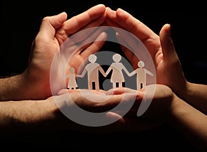 A family of paper holding hands, with the protection of the hands forming a shelter.