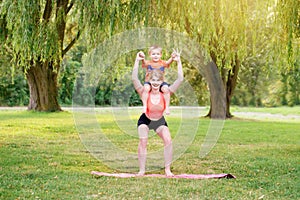 Family parental activity. Young Caucasian mother with child toddler boy doing workout yoga fitness outdoor in park on summer day.