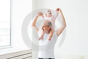 Family, parenthood and fatherhood concept - happy father playing with little baby girl at home