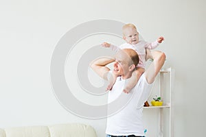 Family, parenthood and fatherhood concept - happy father playing with little baby girl at home